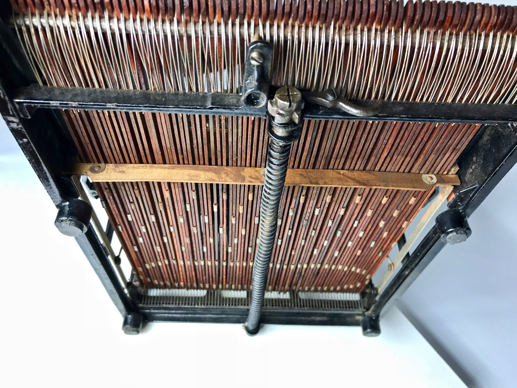 View of the wooden key levers and carriage spring from underneath the machine.